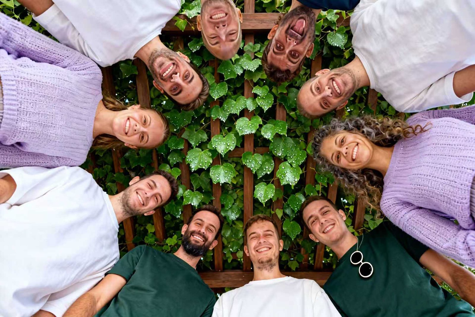 Our dedicated team smiling in a circle under a leafy canopy, representing our shared passion for sustainable hydroponic agriculture